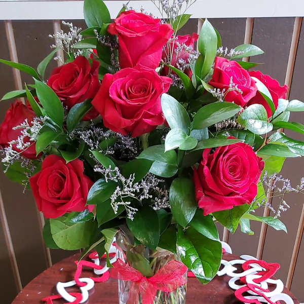 Bouquet of red roses in a clear glass vase with a red ribbon