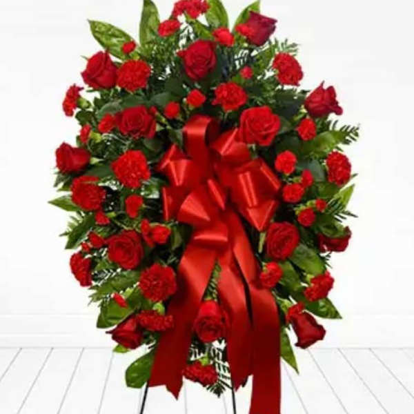 Red rose and carnation standing spray with a large red ribbon