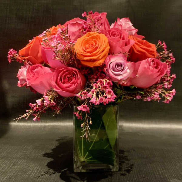 Pink and orange roses arranged in a clear glass vase