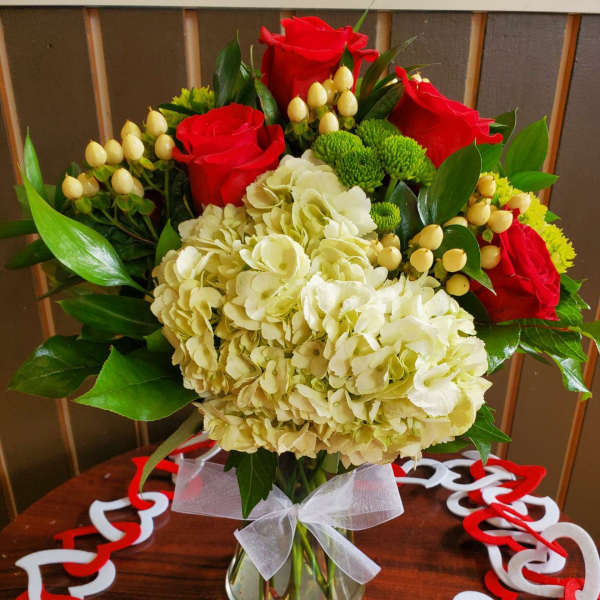 Bouquet of red roses and cream hydrangeas in a glass vase