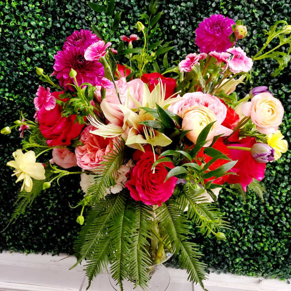Mixed bouquet of pink and red flowers in a clear glass vase