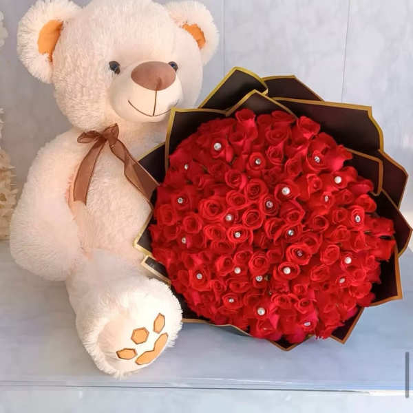 Teddy bear beside a bouquet of red roses in black wrapping