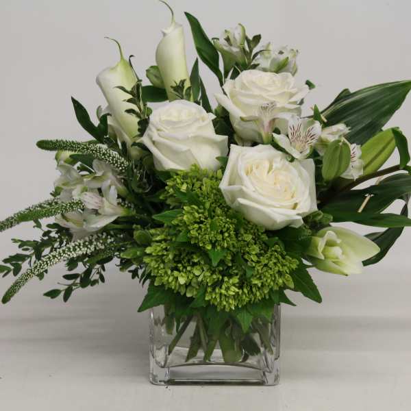 White roses and calla lilies in a clear glass vase