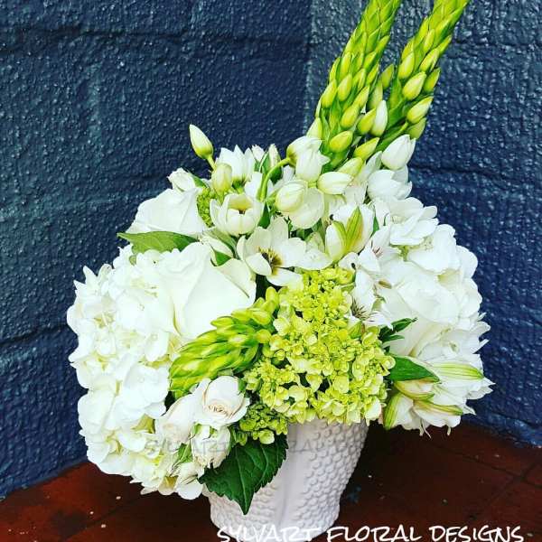 White floral arrangement in a textured white vase with green accents