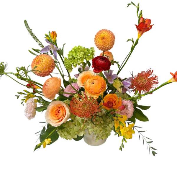 Mixed bouquet in a low vase with orange, red, and green blooms