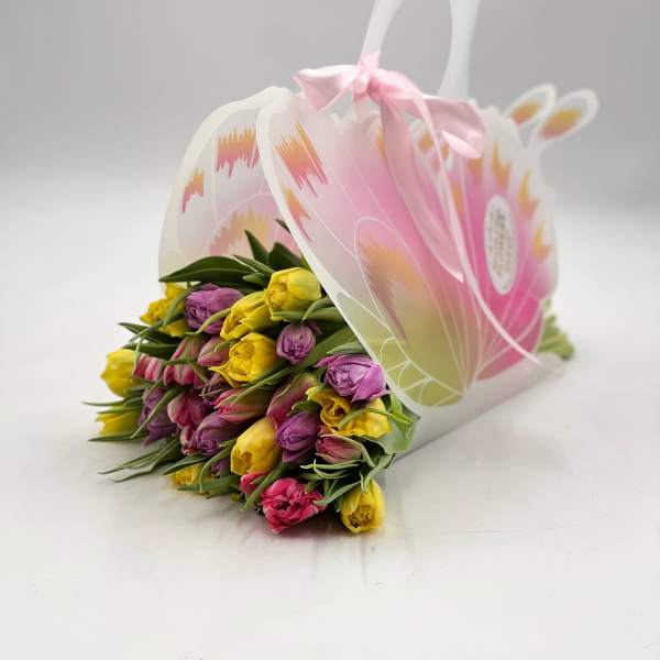 Bouquet of pink, yellow, and purple tulips in a decorative gift bag