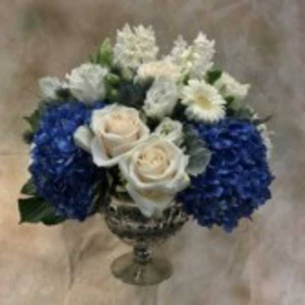 Blue and white flower arrangement in a silver vase