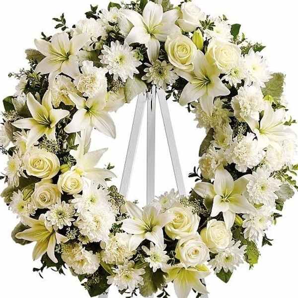 White floral wreath on a standing easel with ribbon