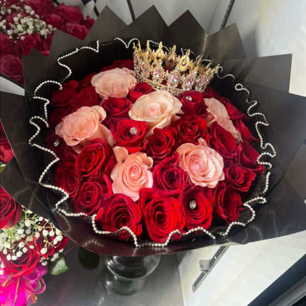 Bouquet of red and blush roses with a jeweled crown in black wrap