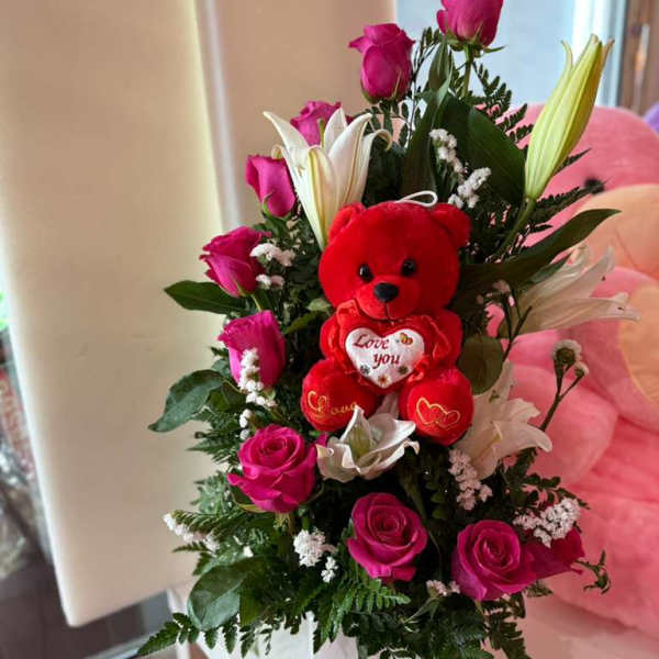 Pink roses and white lilies arranged with a red teddy bear in a white box