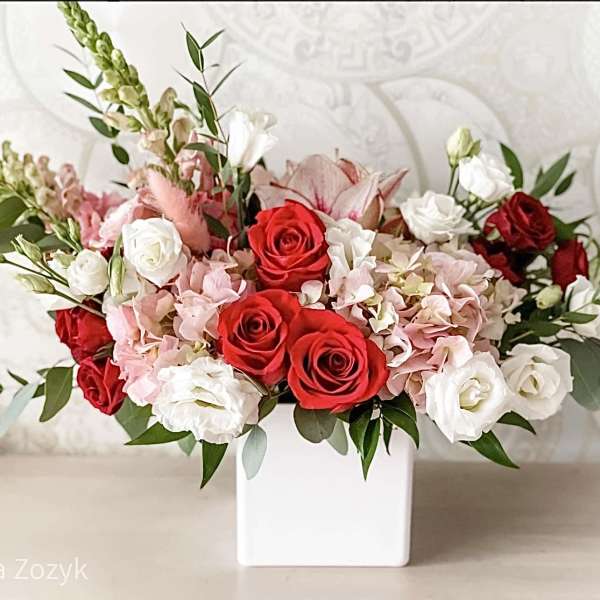 Red and white roses with pink hydrangeas in a white vase