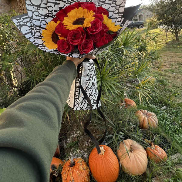 Bouquet of red roses and yellow sunflowers wrapped in patterned paper