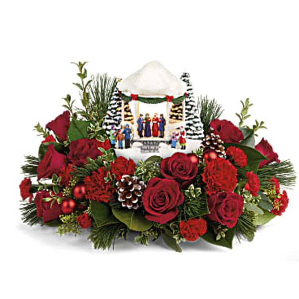 Christmas floral arrangement with red roses and a small nativity scene centerpiece
