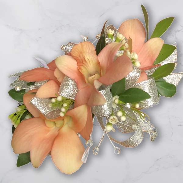 Peach orchid corsage with silver ribbon and green leaves