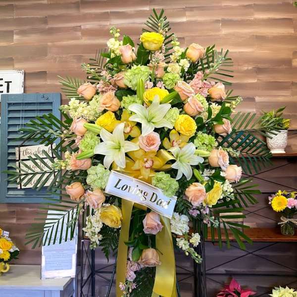 Standing sympathy spray with roses, lilies, and orchids on an easel