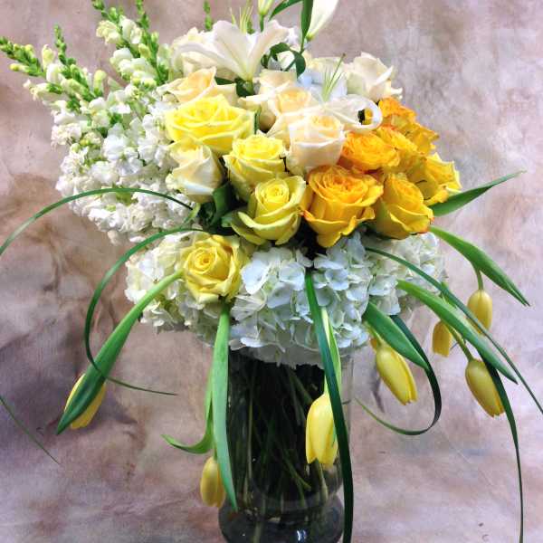 Yellow and white roses with lilies in a glass vase