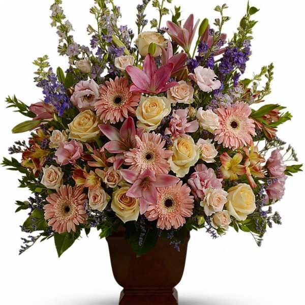 Large pastel arrangement of pink lilies, gerbera daisies, and cream roses in a brown pedestal vase