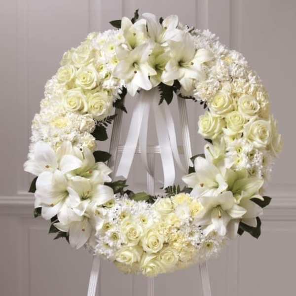 White floral wreath with roses and lilies on a stand