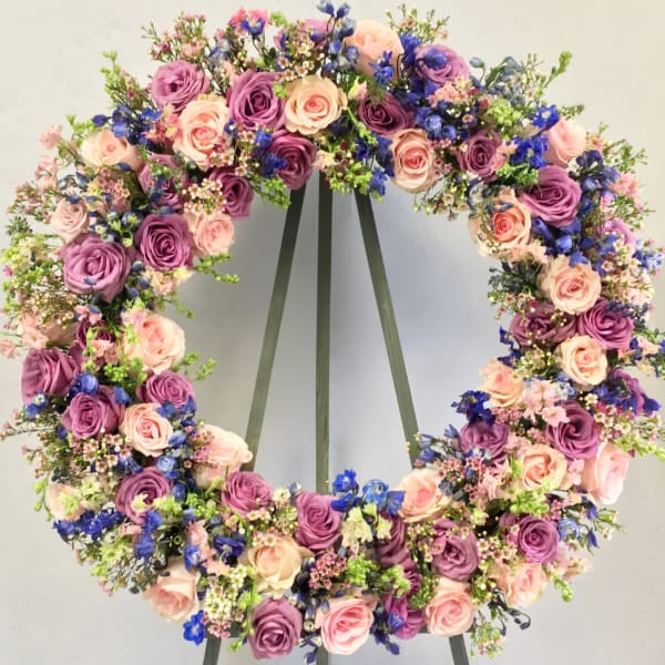 Circular floral wreath with pink, purple, and blue flowers on a stand