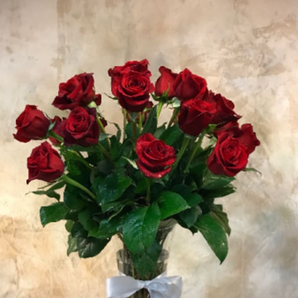 Red roses in a clear glass vase tied with a white ribbon