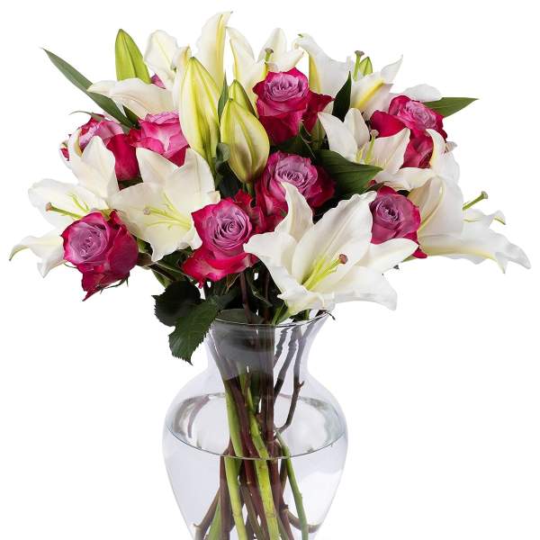 Arrangement of white lilies and bright pink roses in a clear glass vase