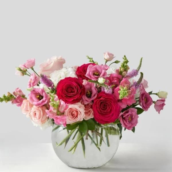 Pink and red mixed flower arrangement in a clear glass vase