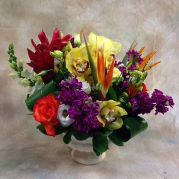 Colorful tropical bouquet in a white pedestal vase