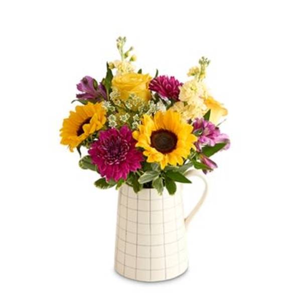 Sunflowers and mixed blooms in a white pitcher vase