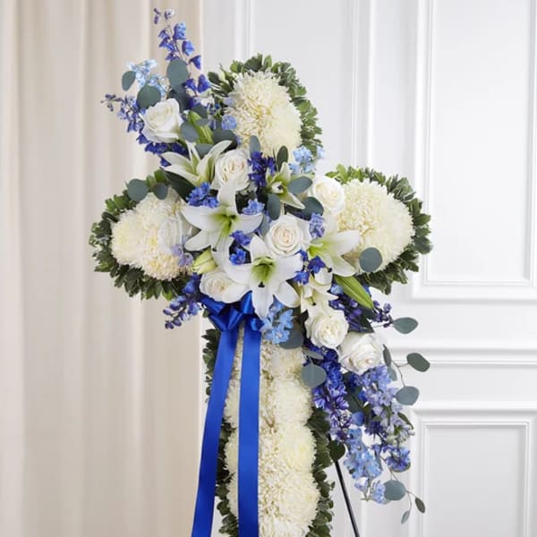 White floral standing cross with blue ribbon and blue flowers