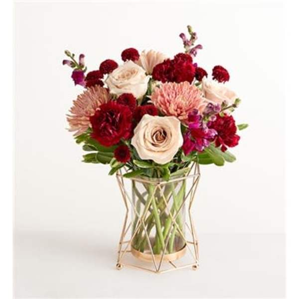 Bouquet of cream, red, and pink flowers in a geometric glass vase