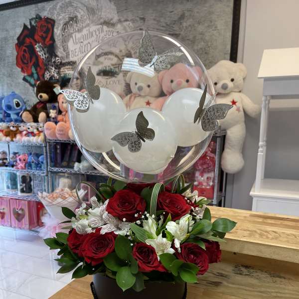 Red roses and white alstroemeria in a round box with a clear balloon topper