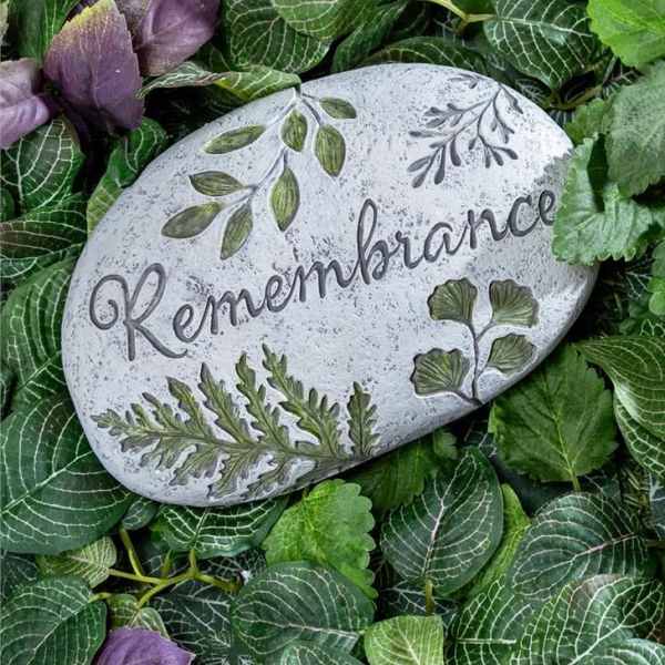 Decorative remembrance stone surrounded by green and purple foliage