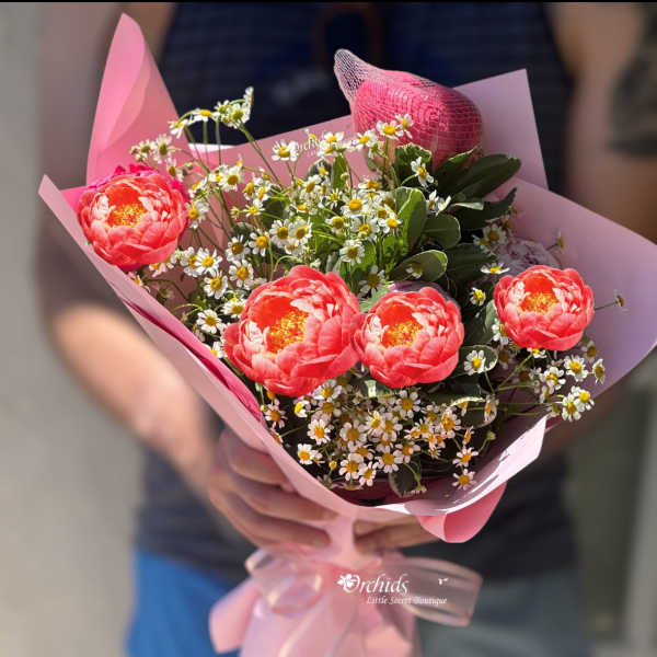 Pink bouquet with coral flowers and small white daisies wrapped in pink paper
