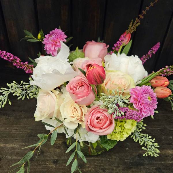 Pink and white mixed bouquet with roses, tulips, and dahlias in a glass vase