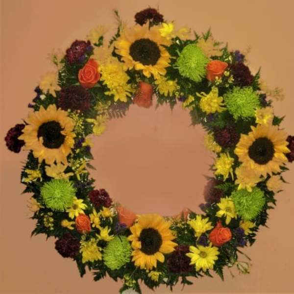 Circular floral wreath with sunflowers, roses, and mums