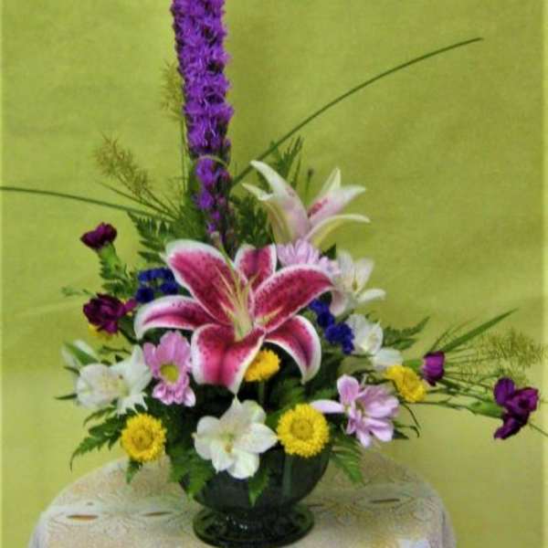 Mixed floral arrangement with pink lilies and purple flowers in a vase