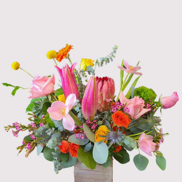 Mixed bouquet with pink lilies, roses, and orange blooms in a wooden box