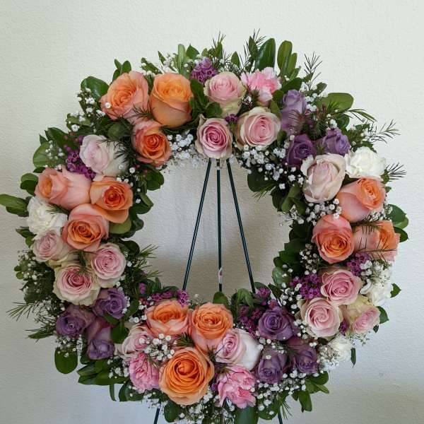Circular wreath of pink, peach, and purple roses on a stand