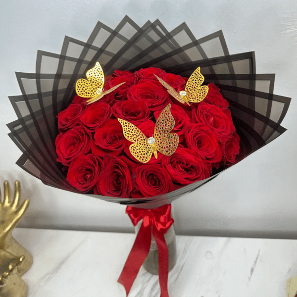 Bouquet of red roses wrapped in black paper with gold butterfly accents