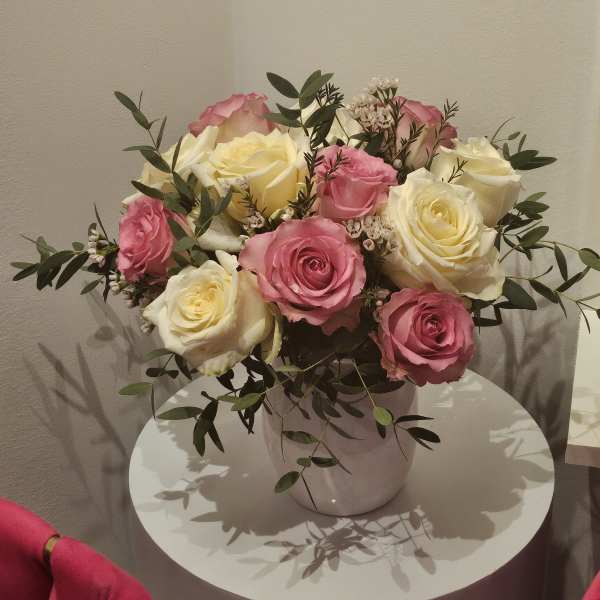 Pink and cream roses arranged in a white vase