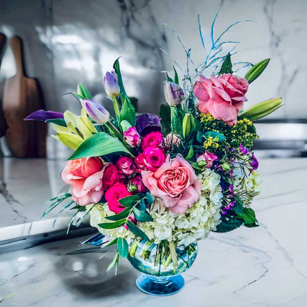 Pink and purple flower arrangement in a blue glass vase