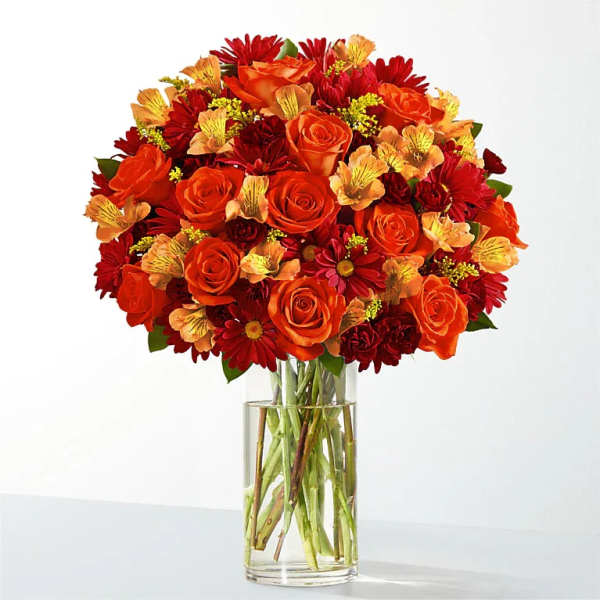 Orange and red flower bouquet in a clear glass vase
