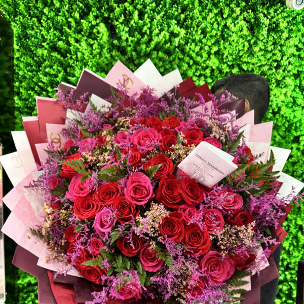 Large bouquet of red and pink roses with purple filler flowers