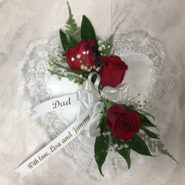 Heart-shaped lace pillow with red roses and a white ribbon