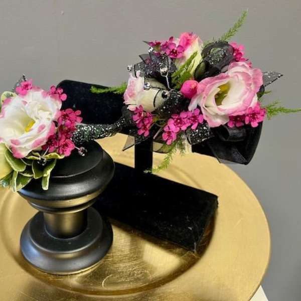 Two small floral arrangements on black stands with pink and white blooms