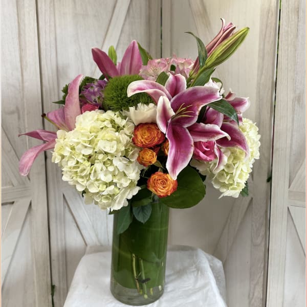 Pink lilies and white hydrangeas in a tall glass vase