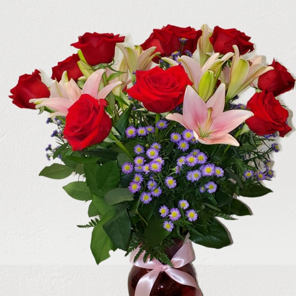 Red roses and pink lilies in a vase with a ribbon