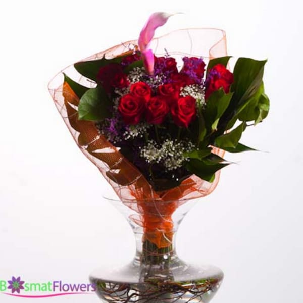 Bouquet of red roses in a clear glass vase with orange wrap