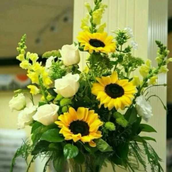 Sunflower and white rose arrangement in a clear glass vase