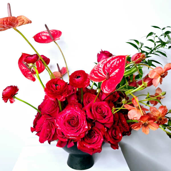 Red roses and anthuriums arranged in a black vase